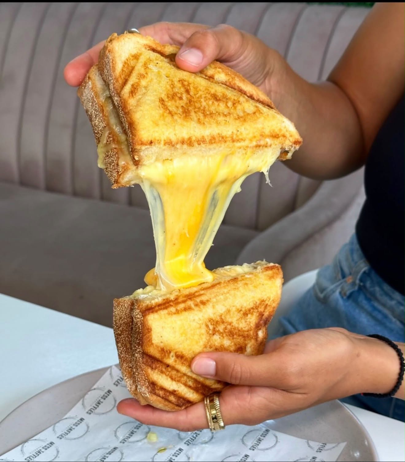 A toasted cheese jaffle being pulled apart with melted cheese stretching between the halves